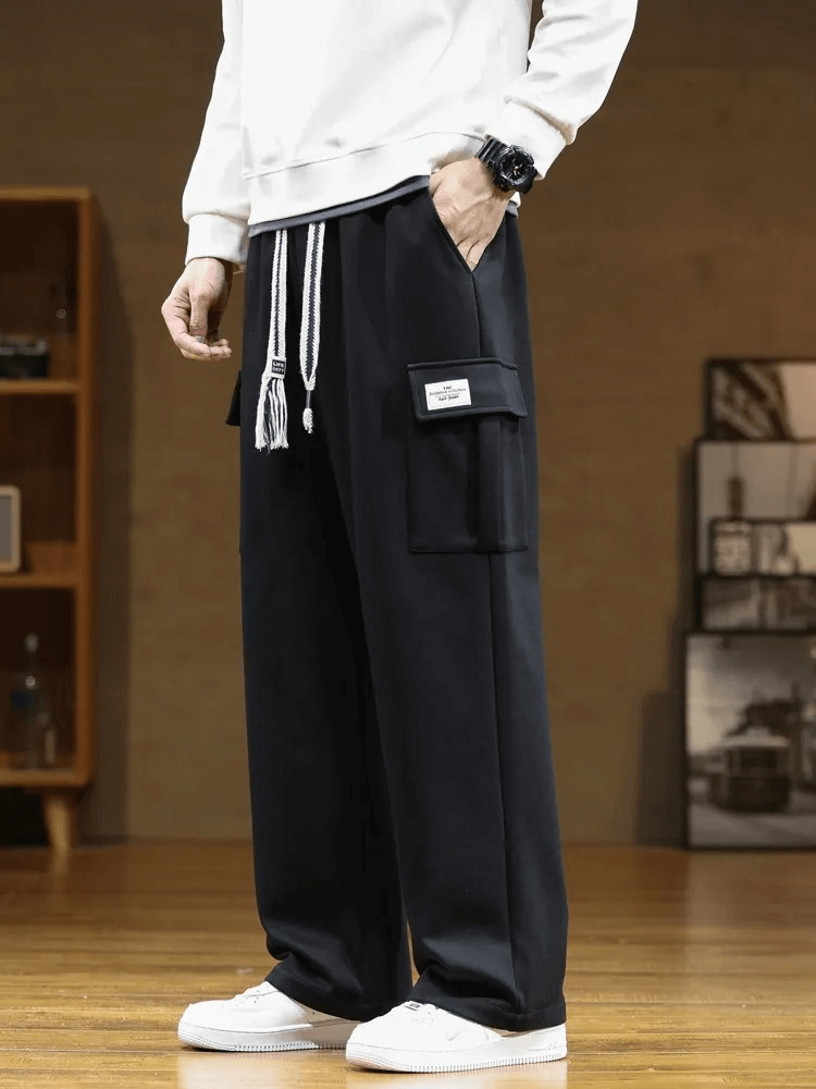 Stylish sports men's pants with several pockets, midrise waist, loose fit, and drawstring closure, ideal for casual athletic style.